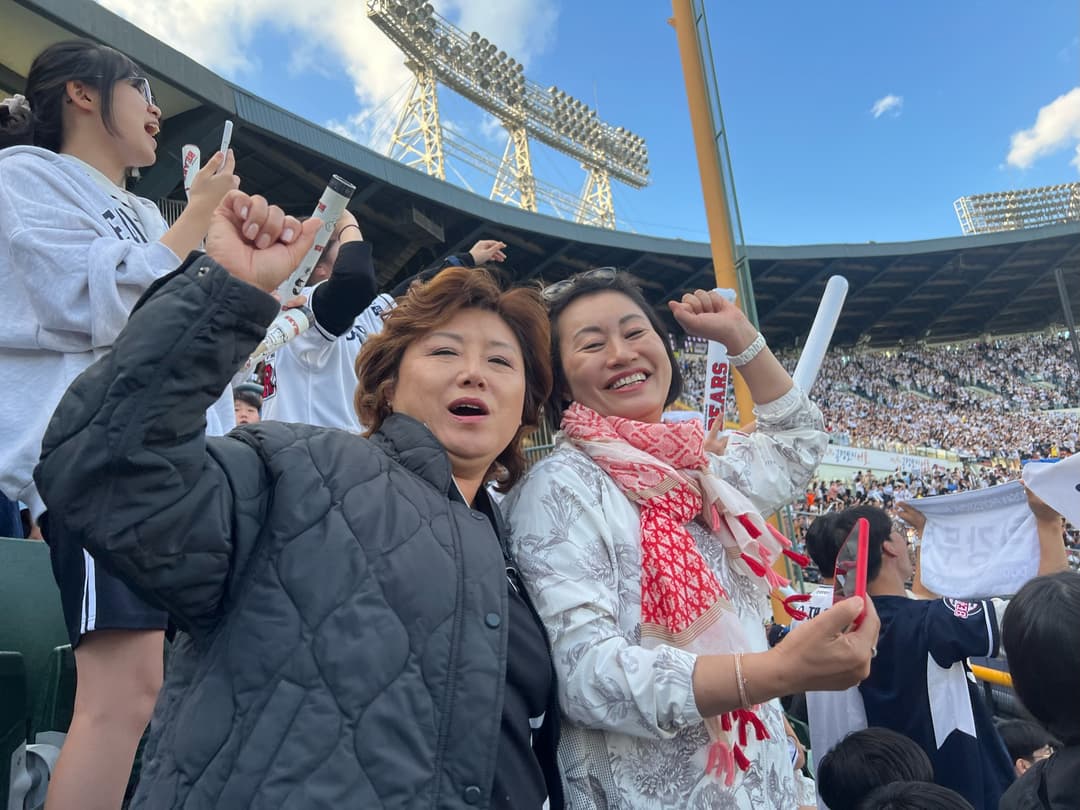 Courtney's mom and friend cheering in the stands at a baseball game